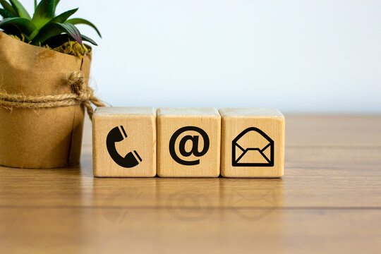 Wooden cubes with mail and phone marks, contact and information icons. Beautiful wooden table, white background. Business concept. Copy space.