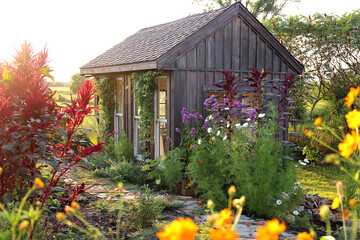 Kleines rustikales Häuschen wie ein Gartenhaus, umgeben von bunten Sommerblumen
