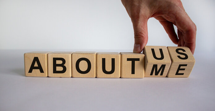 Hand turns a cube and changes the expression 'about me' to 'about us'. Beautiful white background. Business concept. Copy space.
