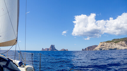 Starboard of a sailboat in the mediterranean sea in the coastline of Ibiza island. Vacation, summer and adventure concept. Calm ocean while sailing.