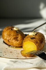 Two baked potatoes with butter, salt and thyme on white plate.