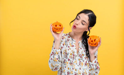 Young woman holding pumpkins on a yellow background