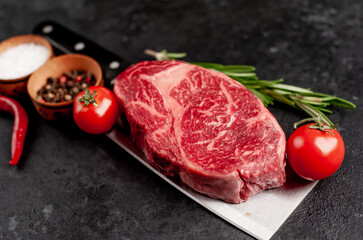 Raw marbled beef steak on a meat knife on a stone background