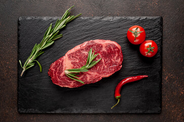 
Raw ribeye beef steak with spices on a stone background