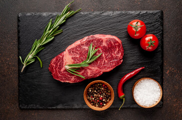 
Raw ribeye beef steak with spices on a stone background