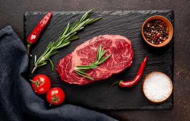 
Raw ribeye beef steak with spices on a stone background