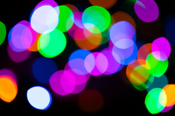 Christmas multicolored lights in defocus on a dark background