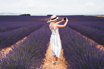 Young excited woman using smartphone on lavender fields