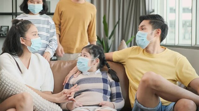 asian family multi generation wearing surgical facial mask together and stay home social distancing together in quarantine between corona virus spread