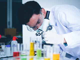 Asian male scientist Is working seriously Chemistry experiment With a microscope In the laboratory, the color tone image.