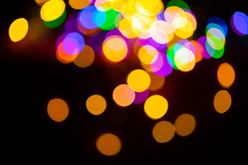 Christmas multicolored lights in defocus on a dark background