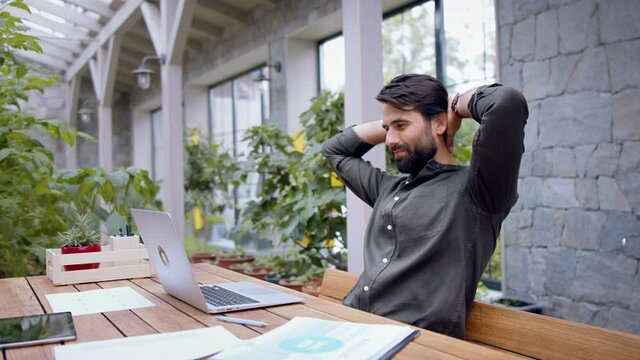 Young man with laptop sitting indoors in green office, working.