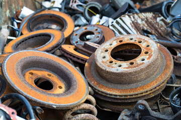 close up on old used and rusty car wheel rotors in a scrapyard