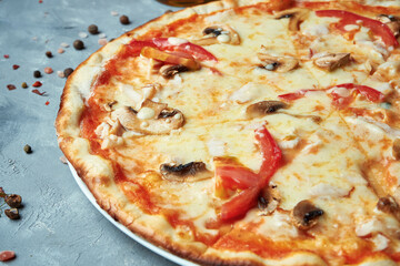 Italian pizza with bacon, mushrooms, tomatoes, melted cheese on a gray background. Top view, food flat lay