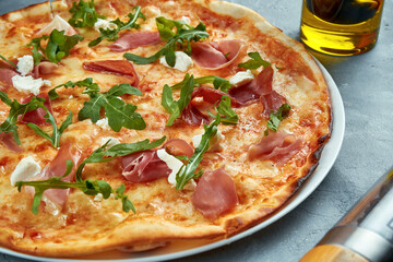 Italian pizza with jamon, arugula and cream cheese on a gray background. Selective focus, food flat lay