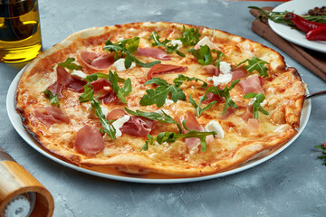 Italian pizza with jamon, arugula and cream cheese on a gray background. Selective focus, food flat lay