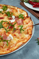 Italian pizza with jamon, arugula and cream cheese on a gray background. Selective focus, food flat lay