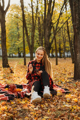 Life Style Portrait of Happy Woman in fall park. Beautiful girl on the nature picnic camping. Relaxing Girl in autumn Nature. Active Outdoor Relax in Nature