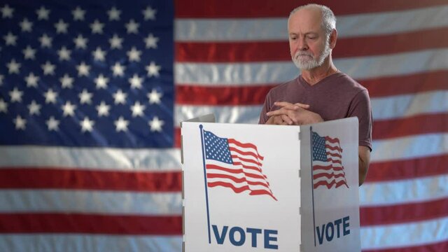 Conceptual portrait on US flag background of funny nervous man in voting booth at ballot box, careful decision for president, in US election.