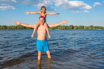 Fototapeta na wymiar Father and daughter have fun playing in the water and posing for the camera. Family outdoor sports games. Holidays, sports, recreation. Active healthy lifestyle concept.