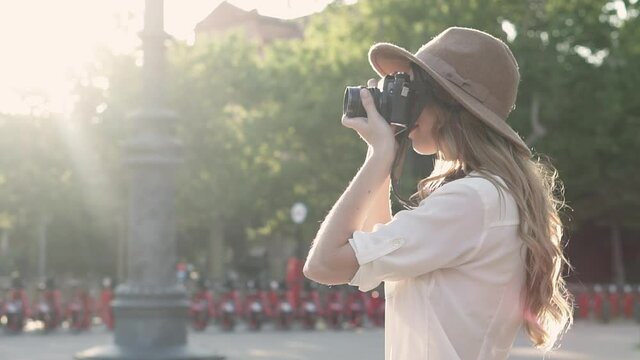 Beautiful solo traveler woman exploring the city of Barcelona and taking photos for a tourism magazine with a vintage analogue camera. Female photographer and tourist taking pictures with film 