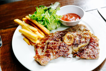 Pork Chop Steak Grilled steaks, French fries and vegetables