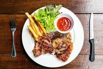 Pork Chop Steak Grilled steaks, French fries and vegetables