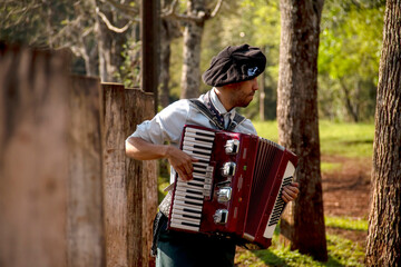 Gaucho boy with typical costumes playing the harmonica outdoors.