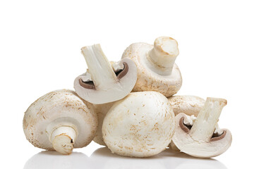 Close up of whole and halved champignons on smooth reflective surface. Button mushrooms isolated on white background