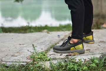 closeout of a sport man feet and a boy running in the park near lake 