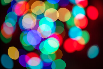 Christmas multicolored lights in defocus on a dark background