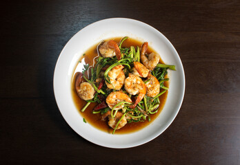 Fried water mimosa with shrimp and oyster sauce in white plate on wooden table