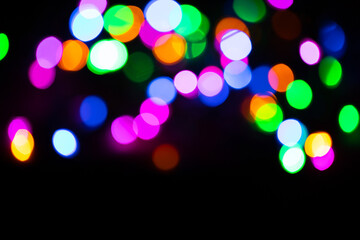 Christmas multicolored lights in defocus on a dark background