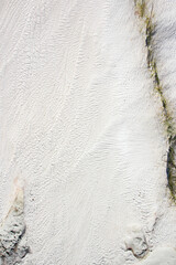 background of white travertine with relief and ribbed surface, green and yellow cracks from algae