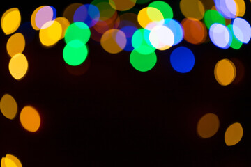 Christmas multicolored lights in defocus on a dark background