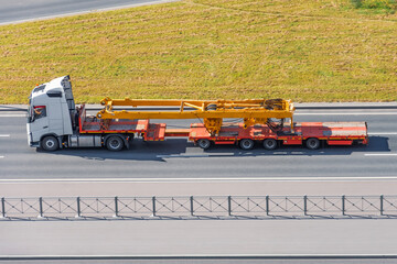 Transportation of tower jib crane components on pltaform truck trailers along the highway.