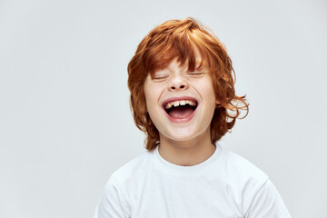 funny red-haired boy with closed eyes with wide open mouth smile cropped view 