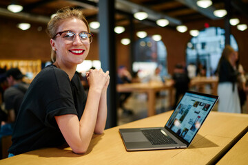 Smiling female worker using computer in cafe