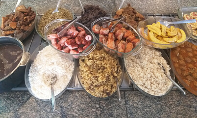 Buffet com carnes, linguiça, arroz, banana assada e feijão