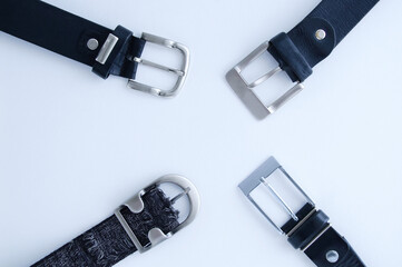 Four metal buckle of a male black leather and textile belt on white background close-up.