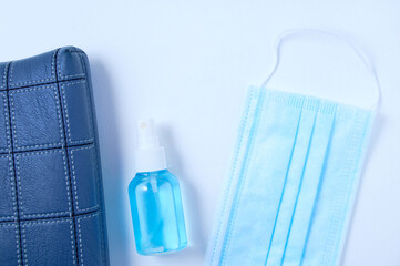 Blue handbag with medical face mask and disinfectant in bottle. White background.
