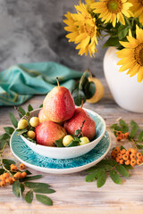 Autumn still life with pears and sunflower flowers on a wooden table
