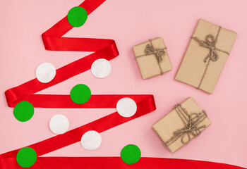 A red ribbon in the shape of a Christmas tree and eco gift wrapping, 2021 year concept.
