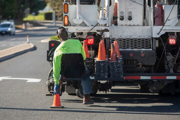 Piant striping truck with seat at the back bumper where a worker sits and places traffic cones onto the street. The truck also has an electonic traffic directional arrow