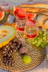 Picnic in the meadow.Wine, French baguette and fruits on the lawn at sunset.