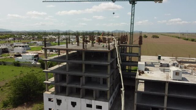 Building works with concrete pump. Crane and building construction site against blue sky