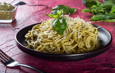 Spaghetti with Basil, Parmesan and garlic pesto. Spaghetti with Basil on a black plate.