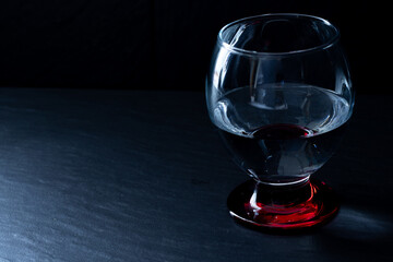 Rotes Trinkglas mit Wasser auf dunkler Fliese