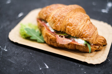 Croissant with ham and cheese arugula and lettuceon, in a paper plate top view