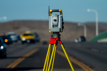 Land survey equipment set up on road with road becoming a hill in the background with traffic